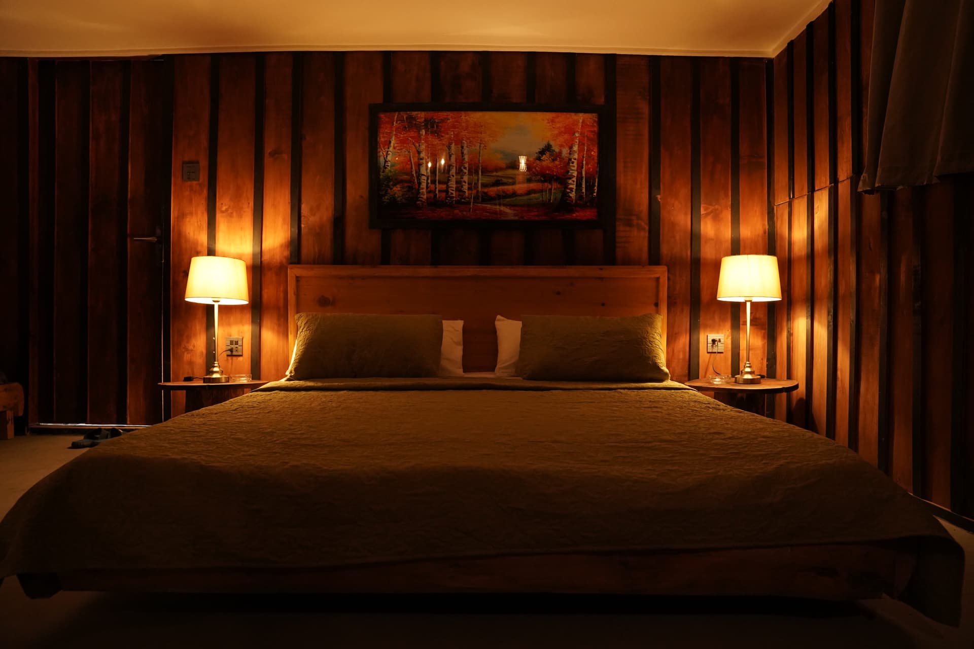 Warm bedroom with wood paneling and landscape art