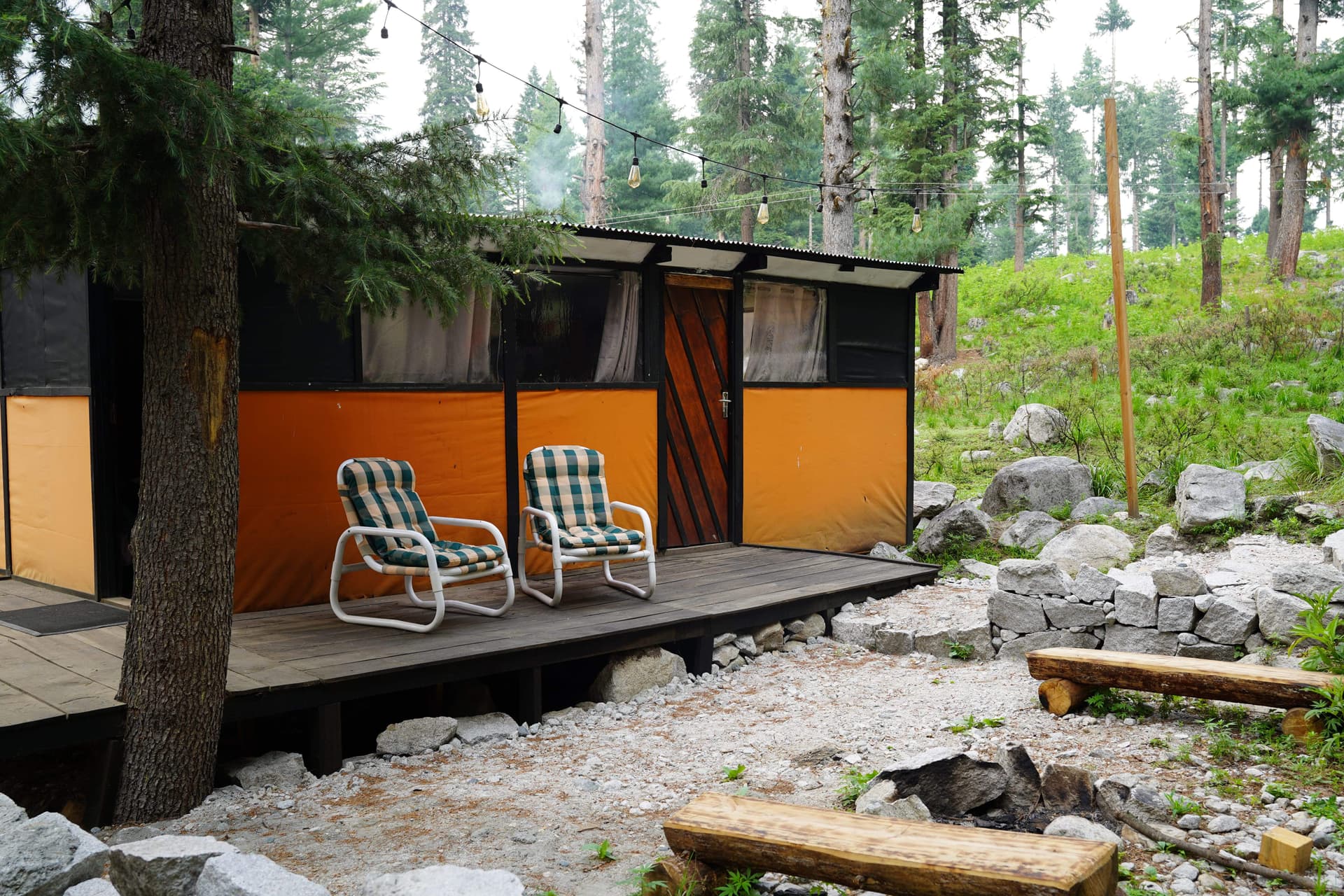 Orange and black cabin with striped lawn chairs on wooden deck