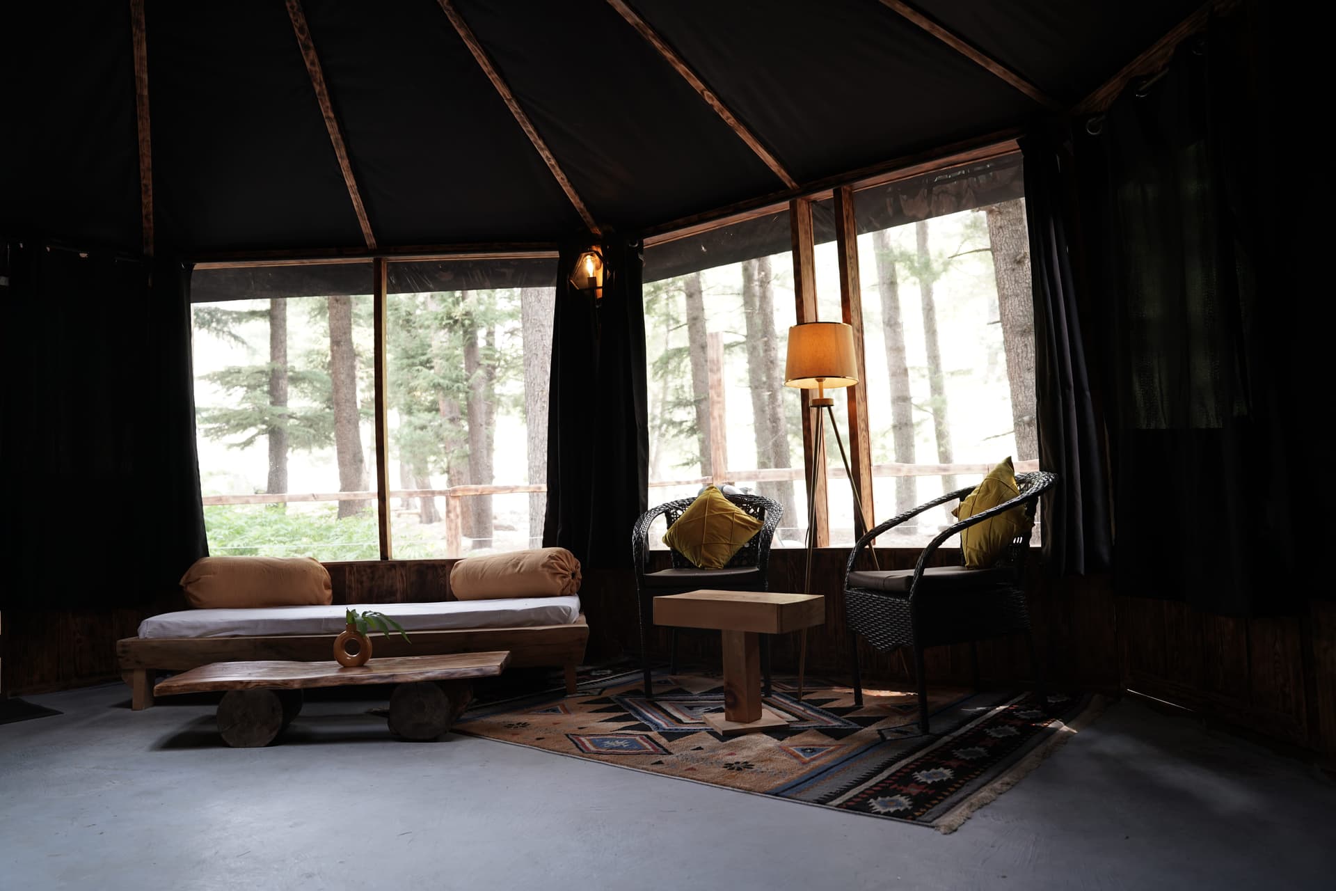 Bright daytime lounge with forest views, wooden daybed, wicker chairs, and natural light