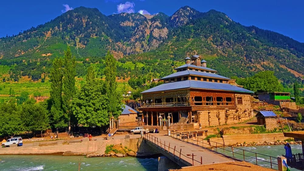 Historic wooden Jamia Masjid mosque with traditional tiered architecture by the river
